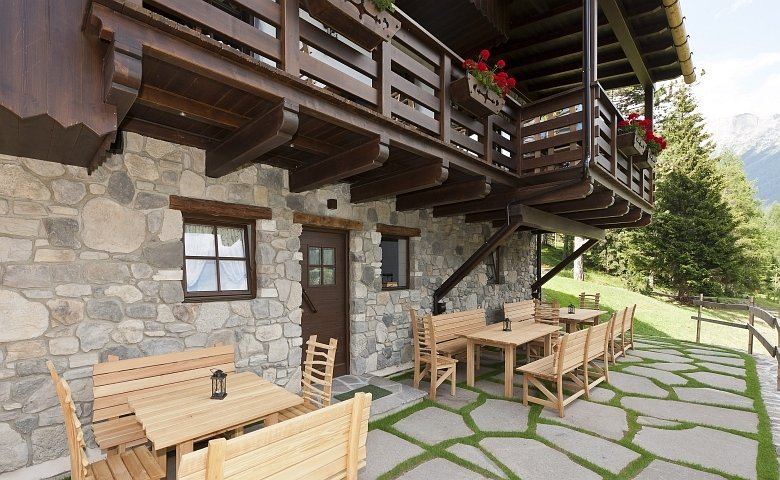 Ambiente interno della baita Malga Roncac con mobilia in legno e pietra